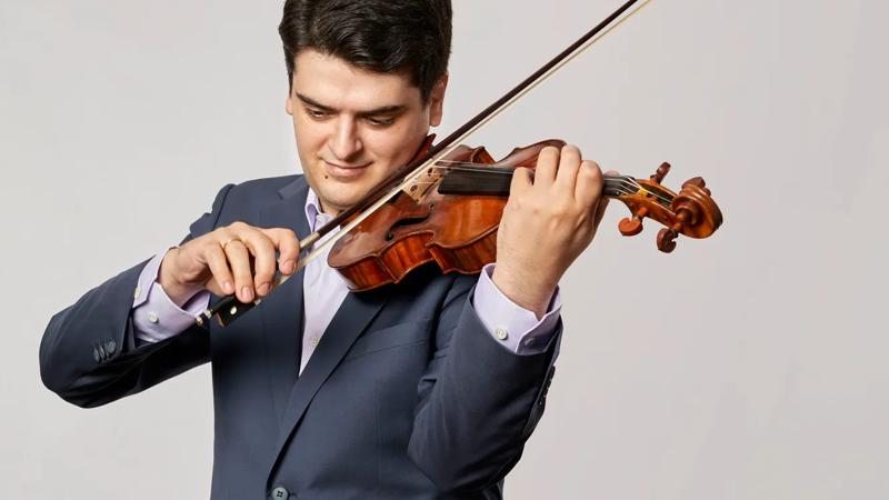 Michael Barenboim in a dark suit, playing a violin
