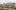 The Royal Festival Hall building viewed from Hungerford Bridge, the trees on the riverside are leafless and some people can be seen walking on Queen\'s Walk