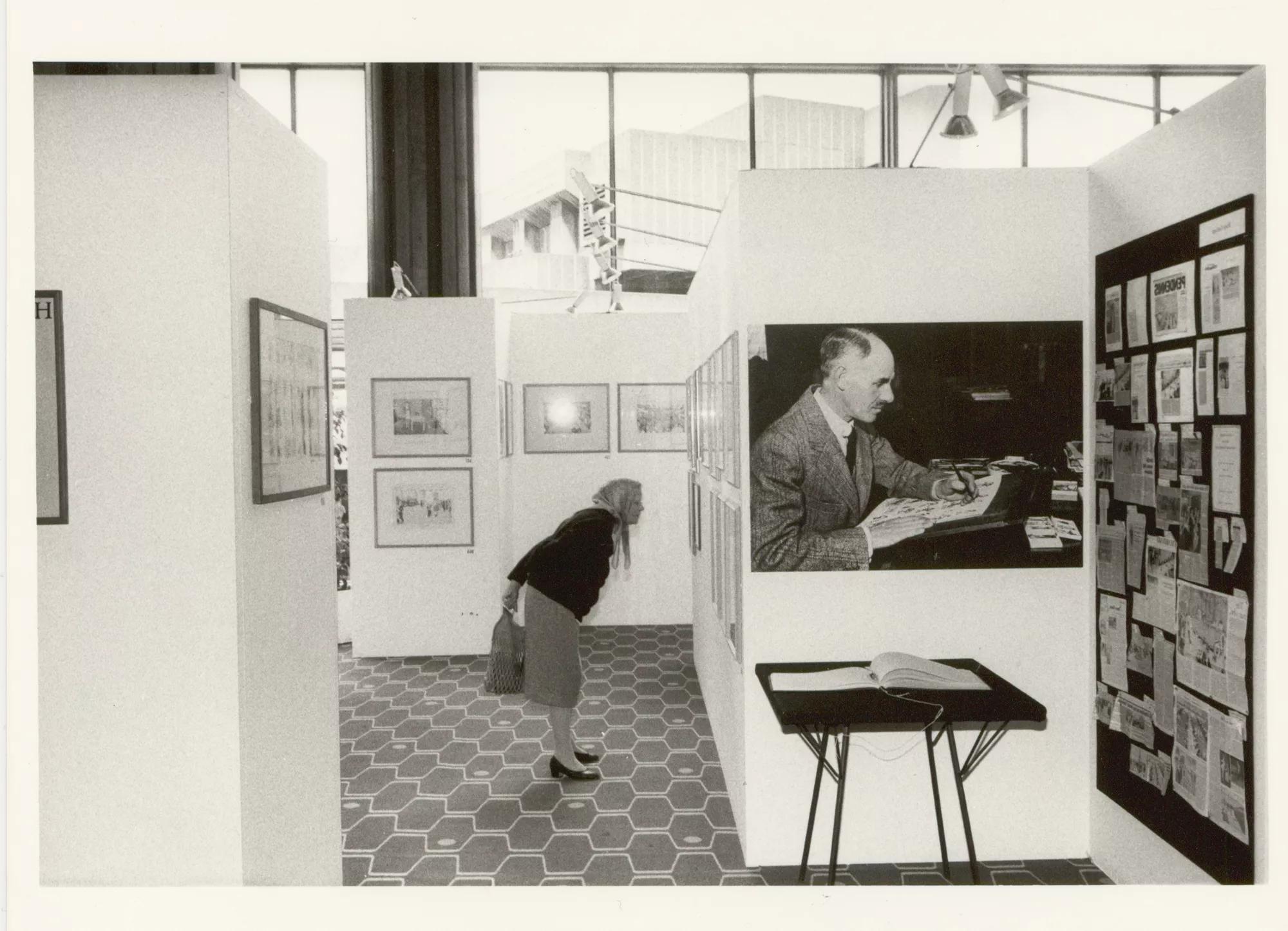 A woman in a headscarf looks at a picture within an exhibition in the Royal Festival Hall foyer space