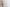 Against a plain white background, a man in white boxers stands with a brooding expression and a natural physique