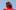 Low angle mid-shot of Southbank Centre Associate Artist Love Ssega, looking down into the camera and wearing a red denim jacket, buttoned-up and with the collar up