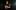 Someone in a dark room playing a wooden accordion