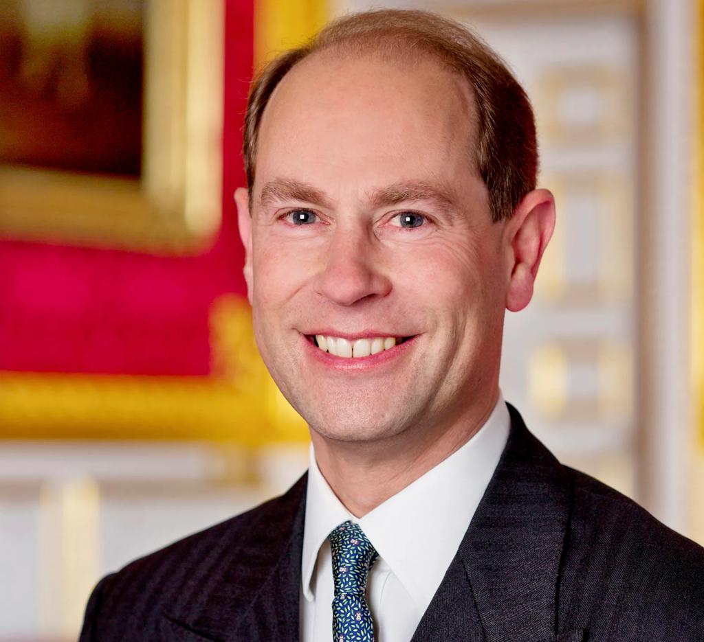 A headshot of His Royal Highness The Duke of Edinburgh wearing a suit, sitting in a regally decorated room