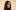 Profile of woman with long brown hair, wearing a black shirt, looking over her shoulder