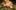 Someone in a gold lace dress lies on patterned green cushions in a dimly lit room.