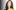 Dua Lipa with long straight brown hair, wearing a satin yellow shirt. 